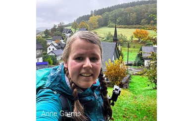 Anne macht ein Selfie im Regen. Hinter ihr befindet sich das Dorf Wirme im Tal