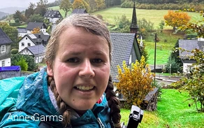 Anne macht ein Selfie im Regen. Hinter ihr befindet sich das Dorf Wirme im Tal